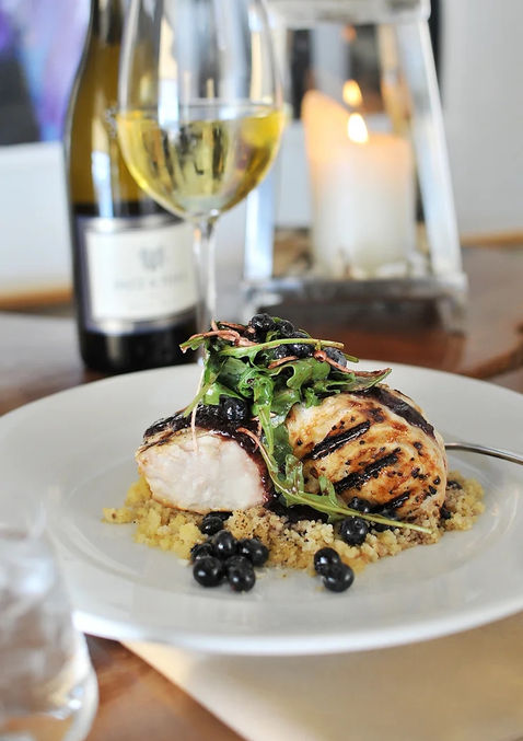 closeup of plated Swordfish next to wine