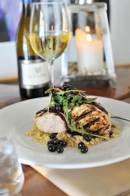 closeup of plated Swordfish next to wine