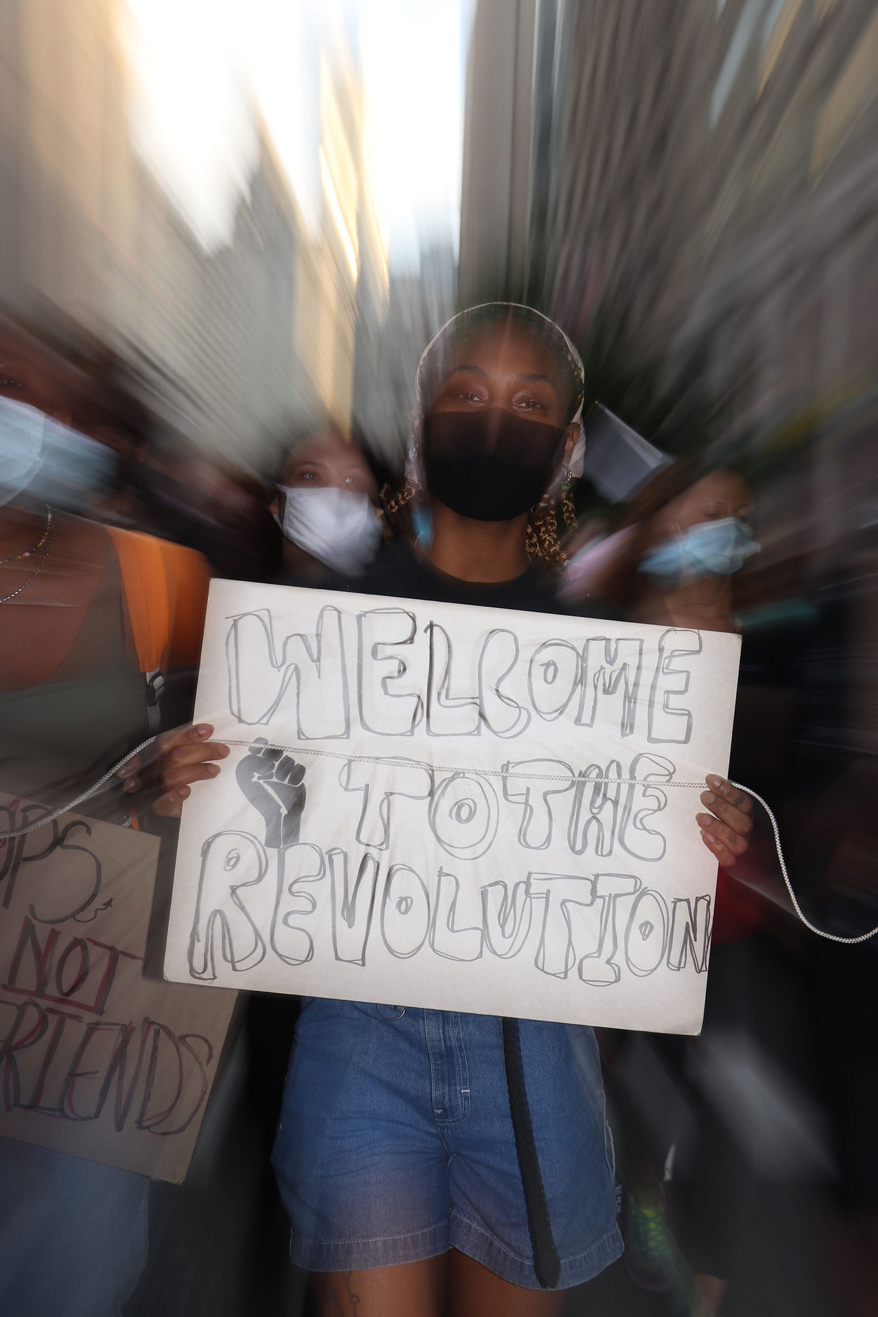 A young woman holds up a sign reading Welcome to the Revolution