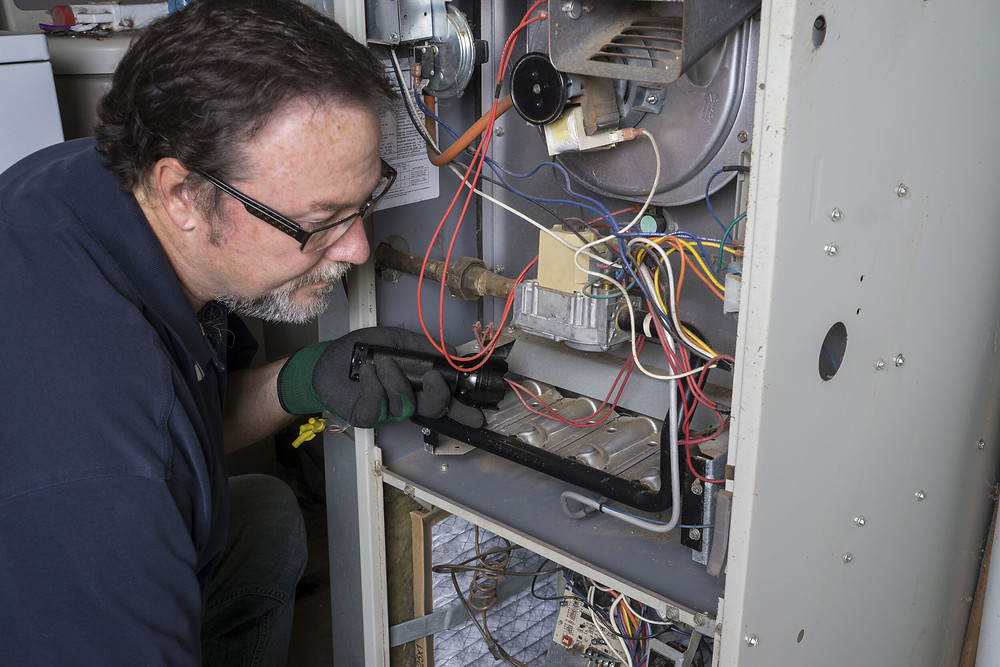 An HVAC technician working on a furnace.