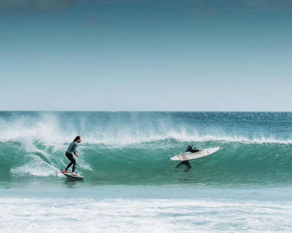 Two surfers riding a turquoise ocean wave — photo by Barna Bartis.