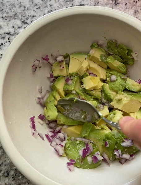 Mixing avocado, red onion, salt, and lime juice for guacamole