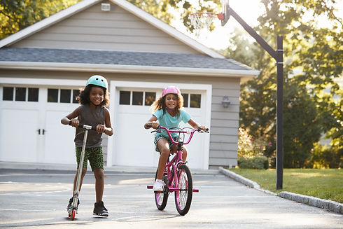 Two girls riding bikes in their driveway