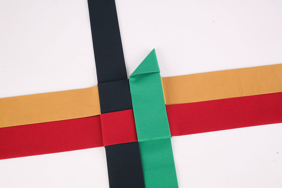 Colorful fabric strips in red, gold, black, and green cross in a woven pattern on a white background.