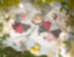 Picnic scene with colorful quilted placemats displaying cake slices. Lemons and greenery surround the setup on a checkered tablecloth.