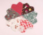 Fabric swatches form a flower shape on a pink background. Patterns include red checks, mushrooms, floral designs, and fruit labels.