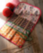 a knitting needle tool roll on a table with yarn and needles