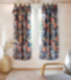 a tropical print curtain made from an old tablecloth hangs over a window with a sofa in the foreground