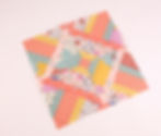 Patchwork quilt square with vibrant patterns, including florals, stripes, and chevrons in pink, yellow, green, and orange on white.