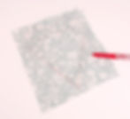 Blue floral fabric with a faint heart outline drawn in pink. A red pen lies beside it on a light background. Creative and calm mood.