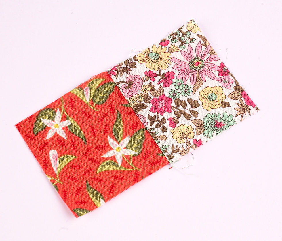 Two overlapping floral fabric swatches, one red and one cream, on a white background with colorful flower patterns.