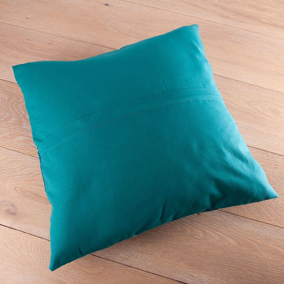 A teal pillow on a light wood floor, showing a simple and relaxed home setting.