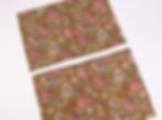 Two pieces of brown floral fabric with pink and cream flowers laid on a white background, slightly overlapping diagonally