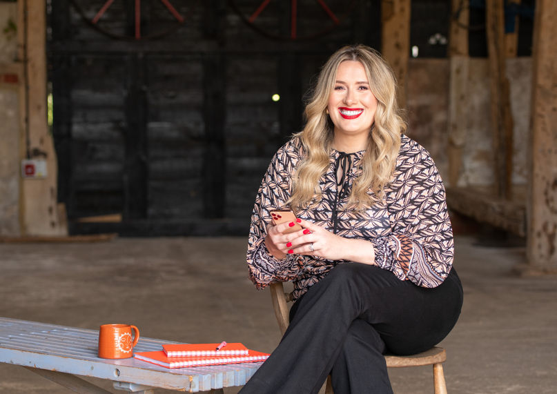 Personal branding photograph showing a woman working on her mobile phone, smiling.