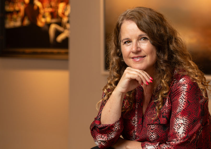 Midlife financial coach sits in a gallery in sevenoaks, posing for her portrait.