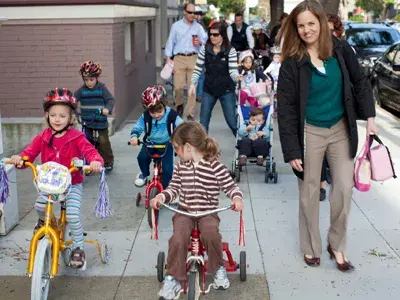 Parents walking with children riding bikes and scooters during a St. James community activity