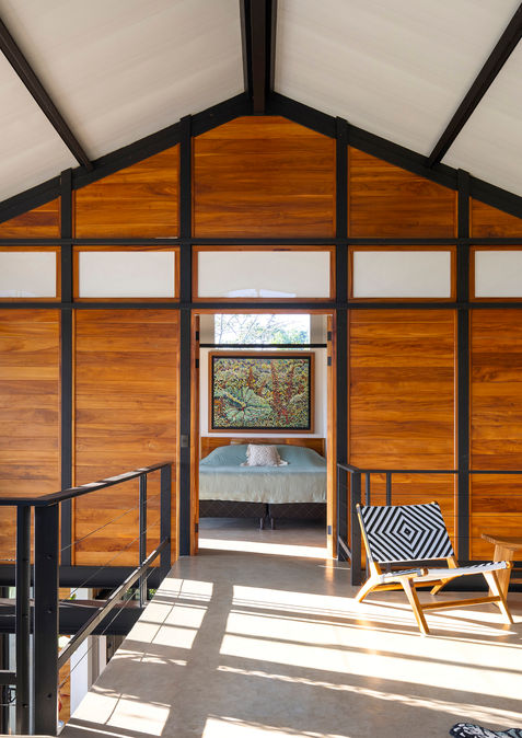Interior of Casa Zenta, featuring a modern loft area with wooden accents, stylish seating, and large windows offering natural light and views of the surrounding nature.