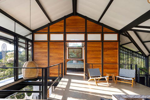 Interior of Casa Zenta, featuring a modern loft area with wooden accents, stylish seating, and large windows offering natural light and views of the surrounding nature.