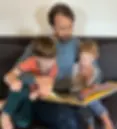 Teacher Leo reading music-themed books with two young students during enrichment