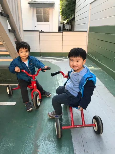 Children riding tricycles and scooters during outdoor play