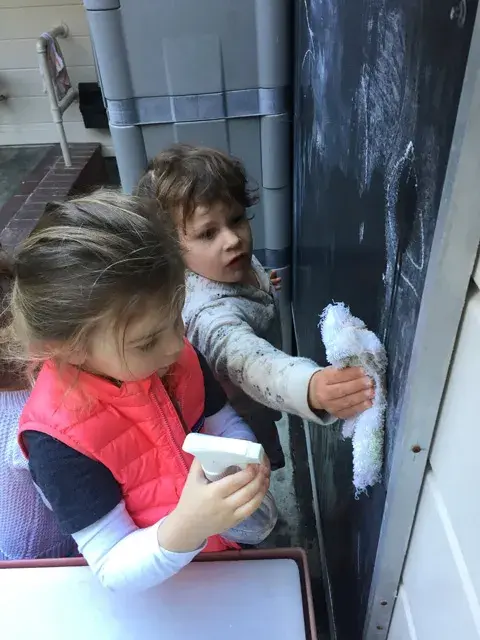 Toddlers washing baby dolls together at a sensory play station