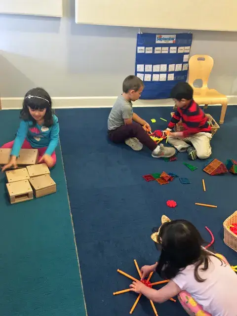 Small group playing a sorting and stacking game on classroom rug