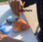 Hands painting a sculpted figure, representing the creation of sculptures, plaster masks, and clay figures by individuals with autism.