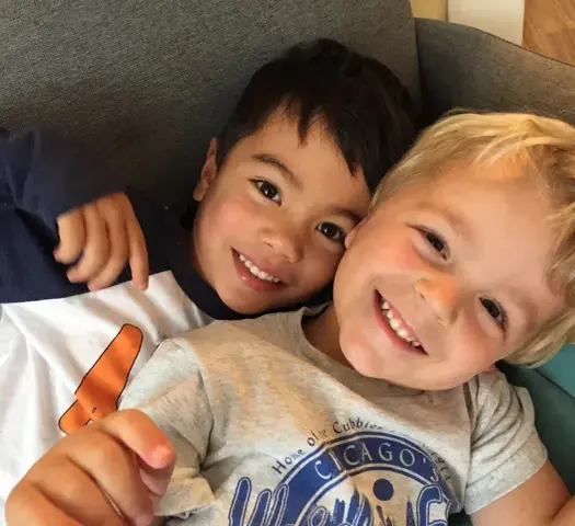 Two preschoolers hugging and smiling during extended day free time