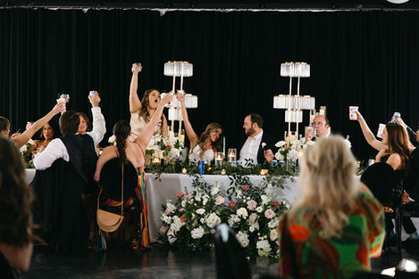 The Maverick Celebratory dinner with people raising glasses, floral decorations.