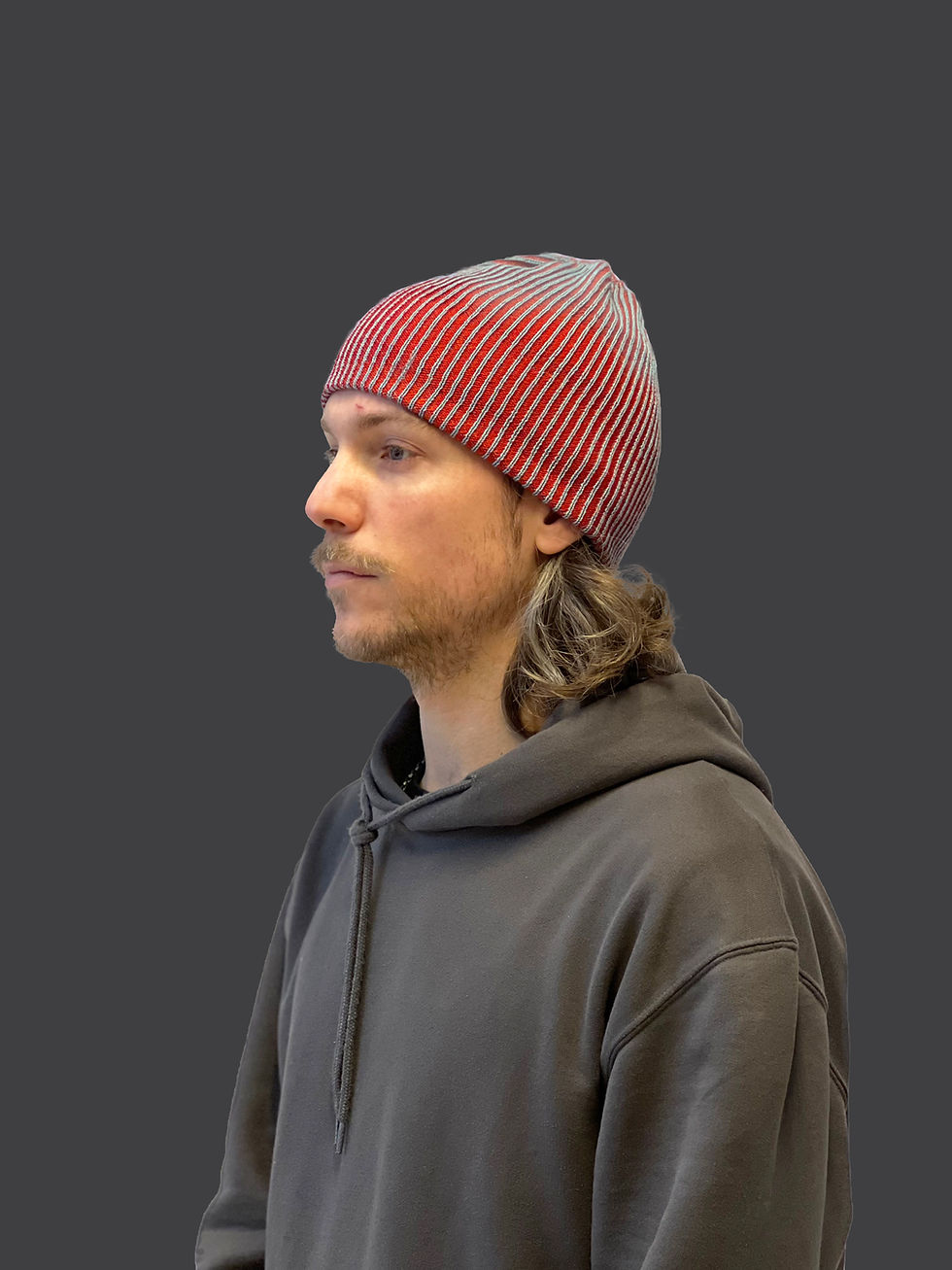 Red and gray knitted beanie crafted from repurposed luxury materials, showcasing sustainable fashion design.
