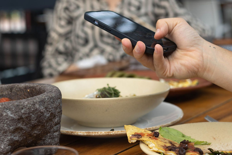 Diner photographing a plated dish with a smartphone at a restaurant table
