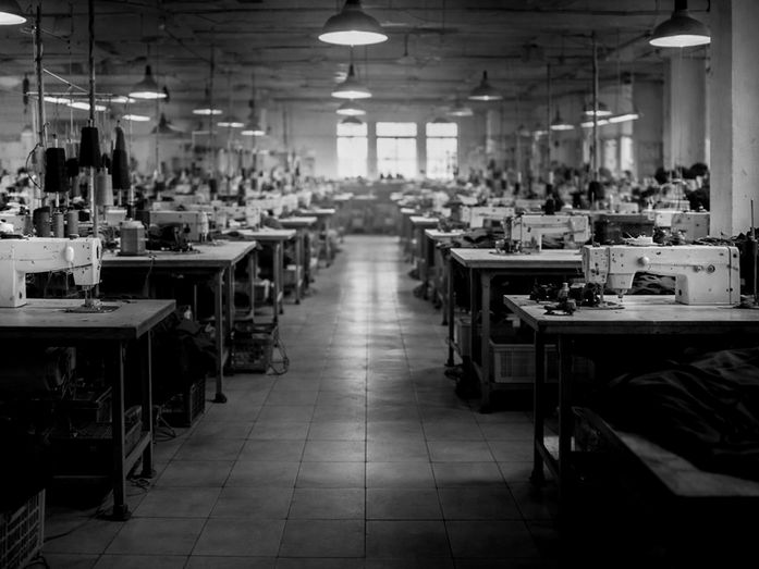 An empty garment factory floor with rows of sewing machines before production begins.
