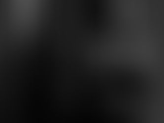 Woman walking through a dim corridor while holding a phone, light falling across the passageway in an evening street scene, photographed by Gary PWK for the Made In His Image project.