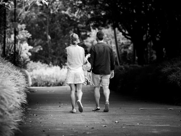 Two people walking side by side, seen from behind, moving forward together.