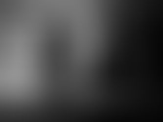 Blurred figures walking past a stone wall, suggesting movement, time, and the quiet weight of what remains carried forward.