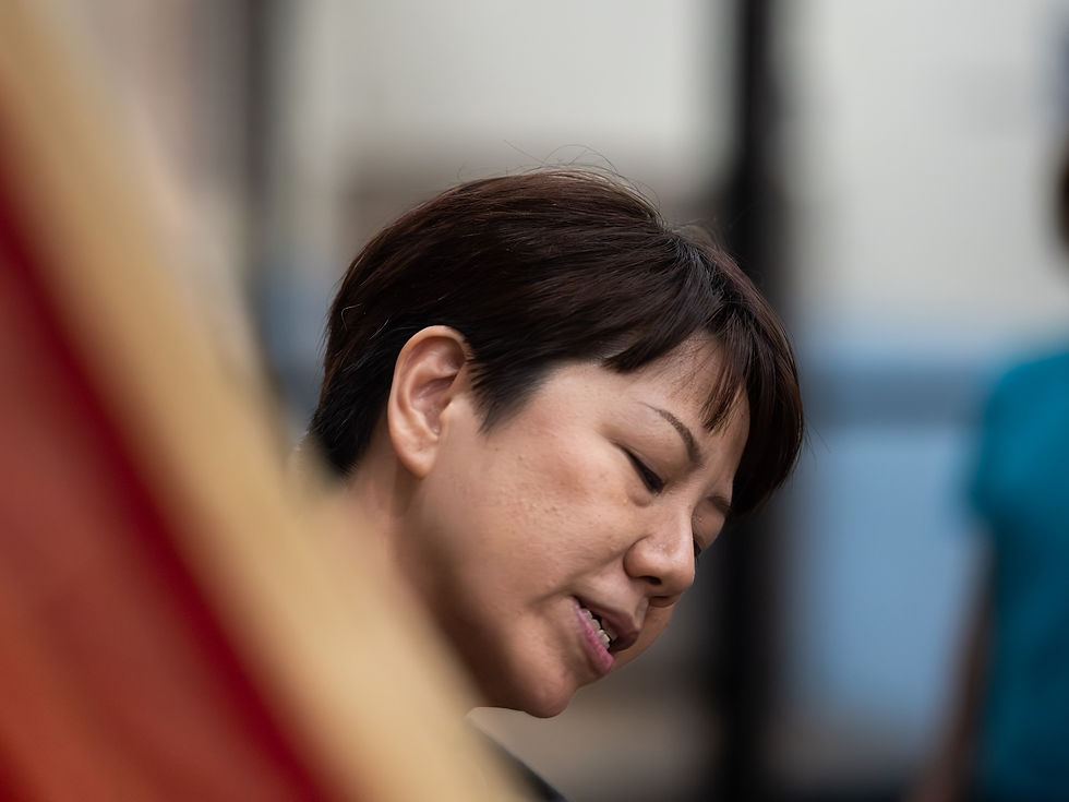 Elaine Chan looking downward during a quiet moment in class, soft foreground fabric partially framing the scene, photographed by Gary PWK for the Made In His Image project.