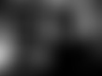 A young man stands alone at night beside a pillar in an urban setting, facing sideways with a still posture as lights blur softly in the background, photographed by Gary PWK for the Made In His Image project.