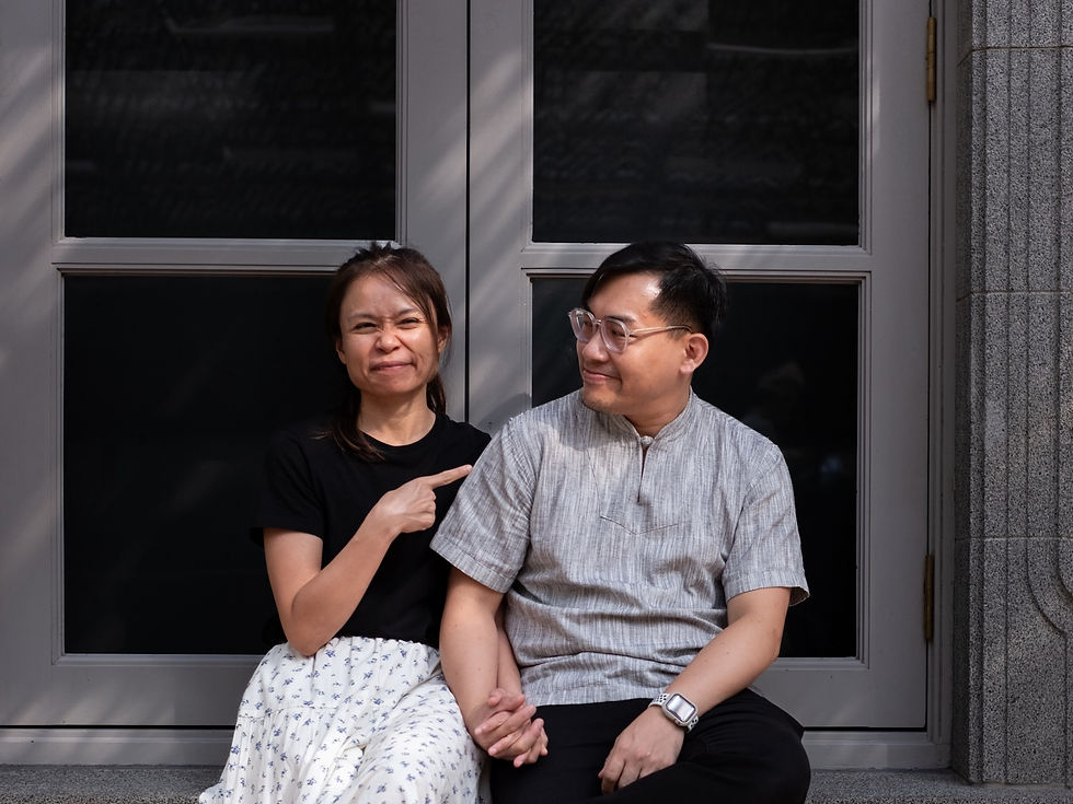 Portrait of Joshua Goh and Mirabel sitting together at the Singapore National Gallery, holding hands while Mirabel playfully points toward Joshua during a Made In His Image portrait session about love and marriage.