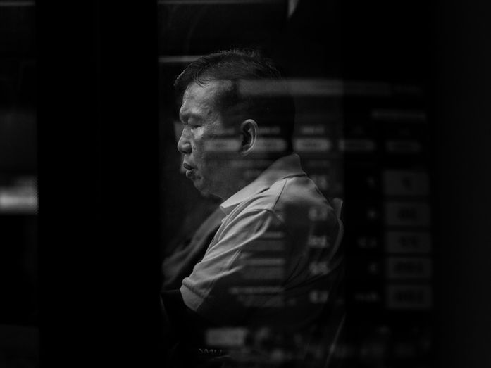 Urban reflection photograph where a figure appears through overlapping glass reflections, symbolising inner dialogue, uncertainty, and shifting self-perception.