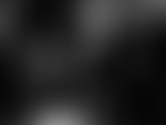 A young man sitting on a bench in a dimly lit public space looking at his phone while others sit nearby, photographed in Singapore for the Made In His Image project, photographed by Gary PWK for the Made In His Image project.