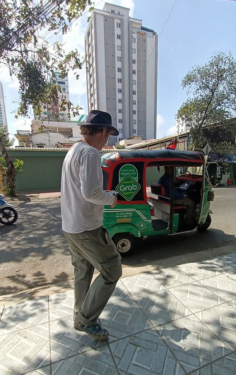 David approaches a green Grab tuk tuk in Phnom Penh, Cambodia.