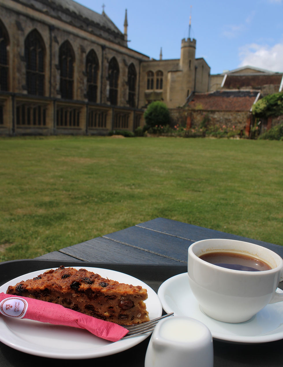 a slice of cake and cup of coffee with St Edmundsbury Cathedral in the background. Pilgrims Kitchen cafe, Bury St Edmunds