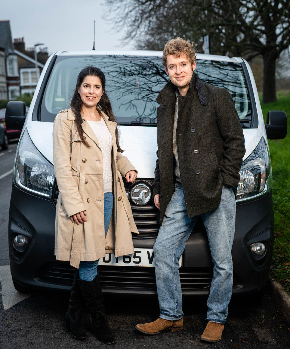 Couple travel bloggers standing in front of a Vauxhall Vivaro van.