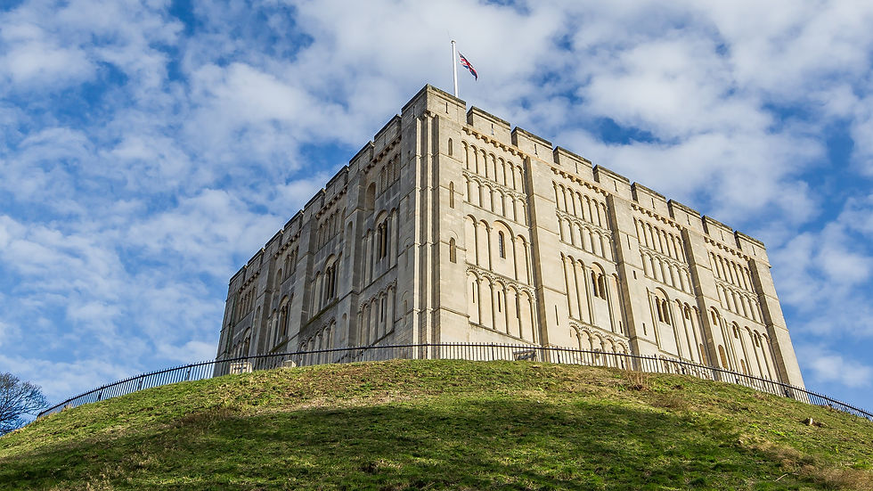 Norwich Castle on a green hill, blue sky behind.