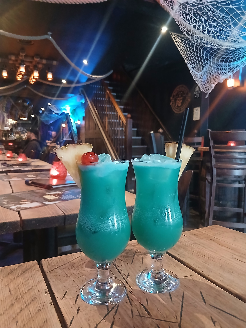 Bright blue cocktails on a wooden table in Rapscallions, Southsea - a pirate themed bar in Portsmouth with nets and ropes hanging decoratively from the ceiling