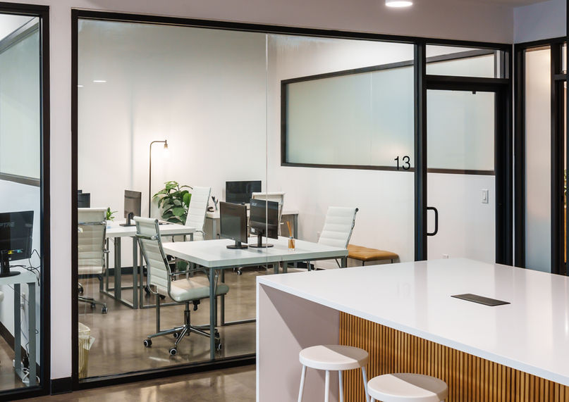 Glass-walled private offices inside a downtown Austin coworking space, featuring modern desks and ergonomic chairs