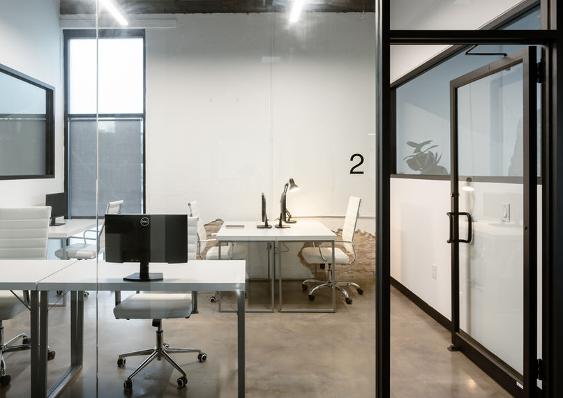 5 modern workstations with white chairs and desks in a clean private office setting.