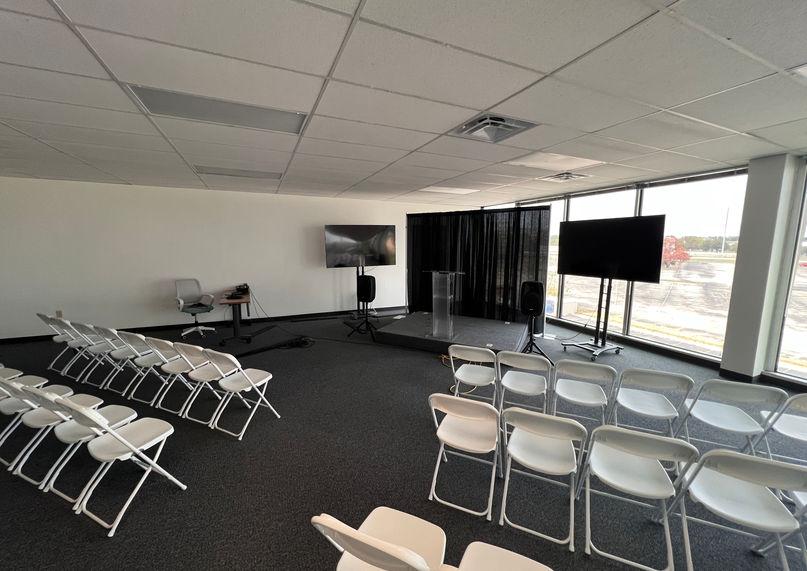 Horizon Hall with TV's on either side of a stage and chairs in rows.
