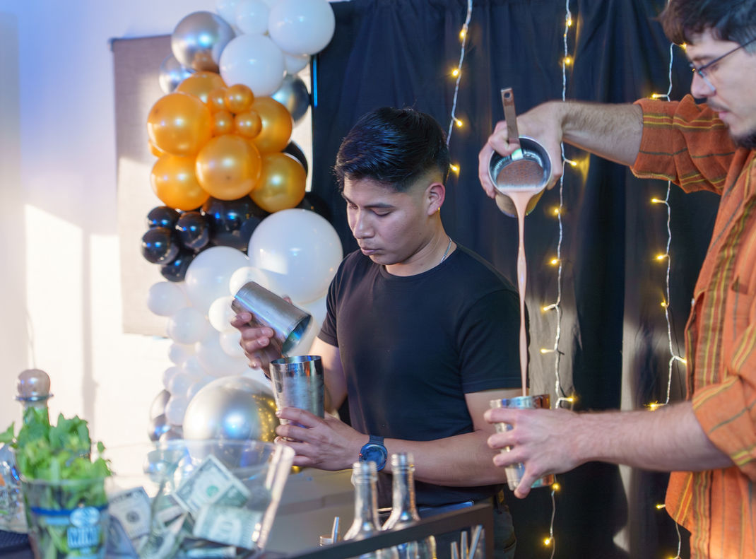 Two bartenders pour drinks in the Waller House Event Space.