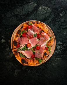 Pizza mit Schinken und Tomaten auf dunklem Hintergrund. Start.